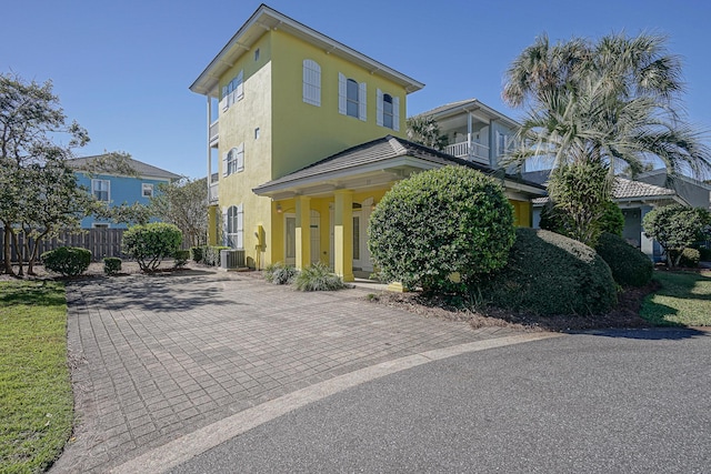 view of front of house featuring fence, covered porch, central AC, and stucco siding