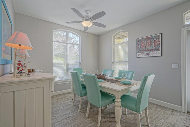 dining room featuring light wood-style flooring, baseboards, and a ceiling fan