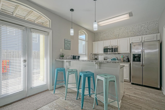 kitchen with a breakfast bar area, light wood-style floors, white cabinetry, and appliances with stainless steel finishes