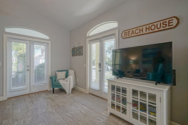 living area with light hardwood / wood-style flooring, french doors, and lofted ceiling