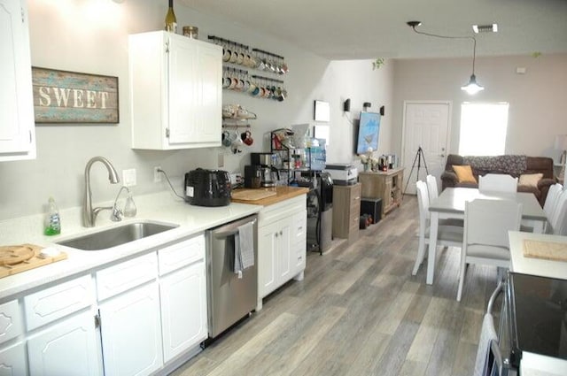 kitchen featuring light hardwood / wood-style floors, decorative light fixtures, sink, dishwasher, and white cabinets