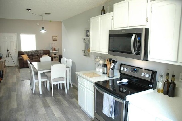 kitchen featuring stainless steel appliances, white cabinets, light hardwood / wood-style floors, pendant lighting, and a textured ceiling