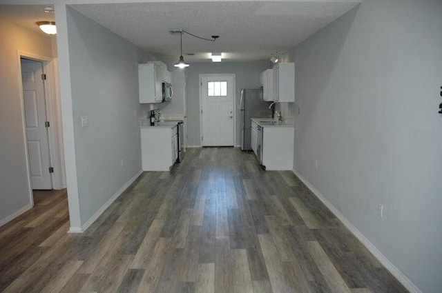 kitchen featuring stainless steel appliances, white cabinets, dark hardwood / wood-style flooring, and a textured ceiling