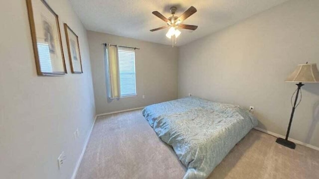 bedroom with ceiling fan, light colored carpet, and a textured ceiling