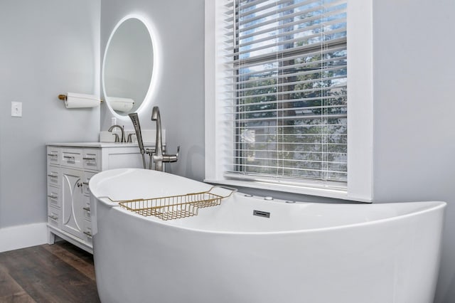 bathroom with hardwood / wood-style flooring, vanity, and a bathing tub