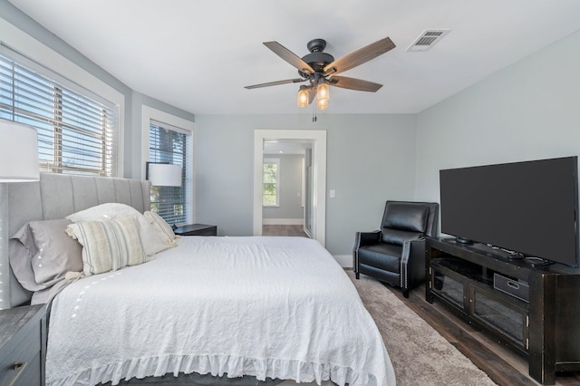 bedroom featuring ceiling fan, dark hardwood / wood-style flooring, and multiple windows