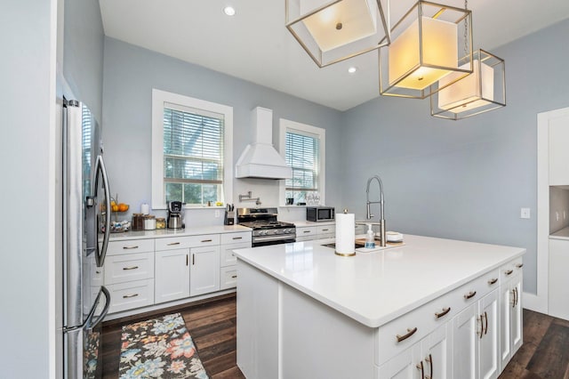 kitchen with an island with sink, premium range hood, dark wood-type flooring, white cabinetry, and appliances with stainless steel finishes