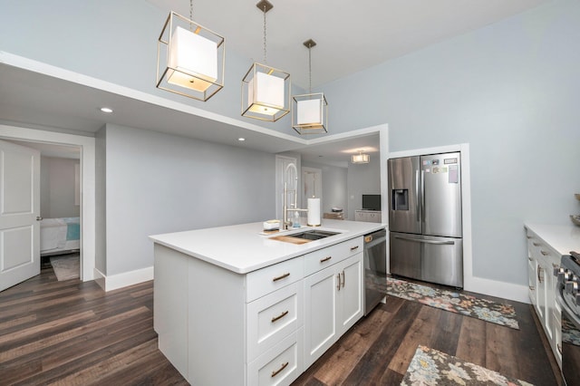 kitchen with a kitchen island with sink, stainless steel appliances, dark hardwood / wood-style flooring, hanging light fixtures, and white cabinetry