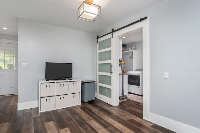 living room featuring dark wood-type flooring, a barn door, and washer / dryer