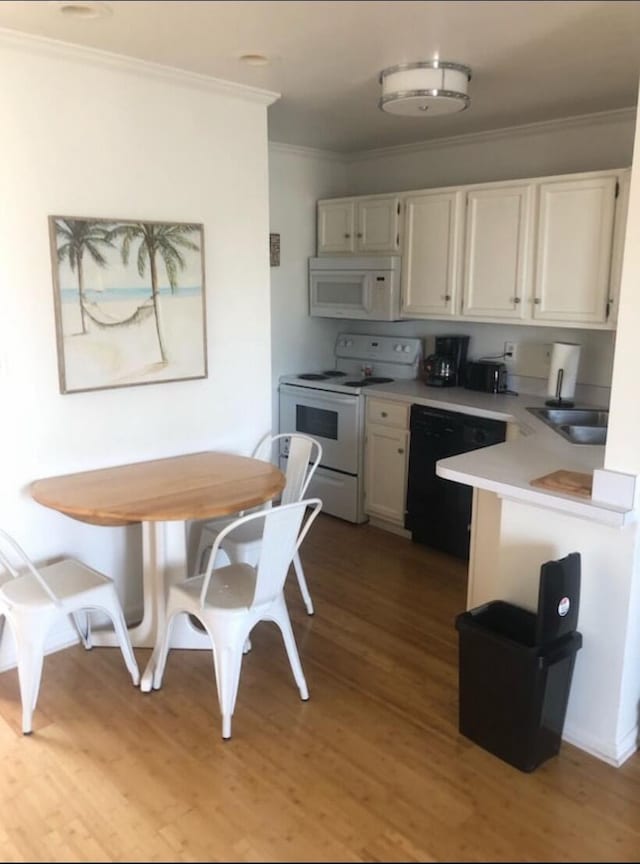 kitchen featuring light wood-type flooring, white appliances, sink, ornamental molding, and white cabinets