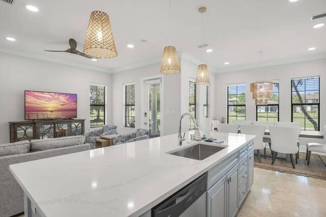 kitchen with pendant lighting, an island with sink, sink, stainless steel dishwasher, and light stone countertops