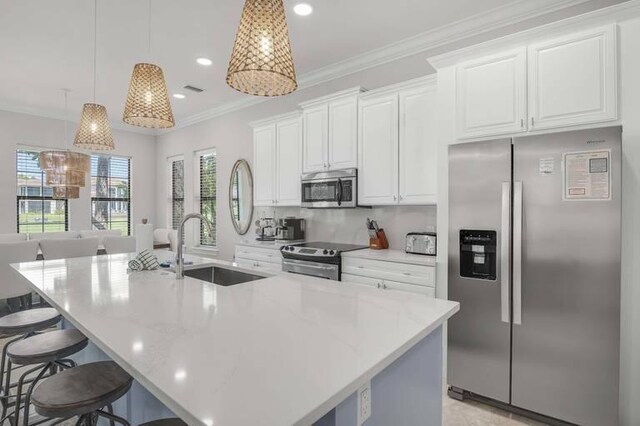 kitchen featuring a center island with sink, sink, hanging light fixtures, white cabinets, and appliances with stainless steel finishes