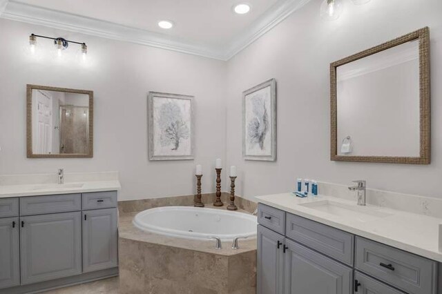 bathroom featuring tiled tub, vanity, and crown molding