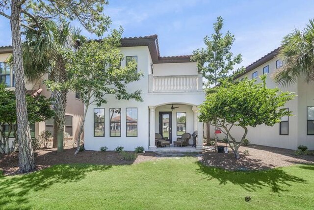 back of house with french doors, a balcony, and a lawn