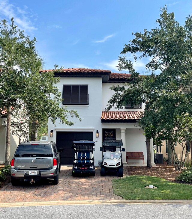 mediterranean / spanish-style home featuring central air condition unit, a garage, and a front yard