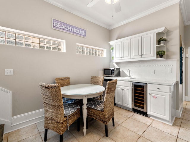 dining room with wet bar, ornamental molding, beverage cooler, and light tile patterned floors