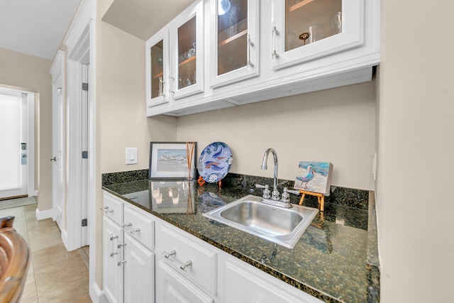 kitchen with white cabinetry, sink, dark stone counters, and light tile patterned floors