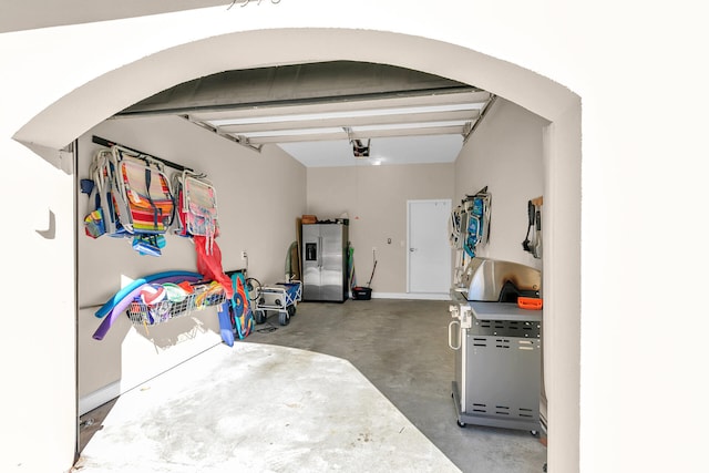 garage with a garage door opener and stainless steel fridge with ice dispenser