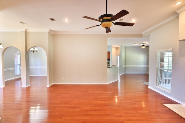 unfurnished room featuring ceiling fan with notable chandelier, crown molding, and light hardwood / wood-style floors