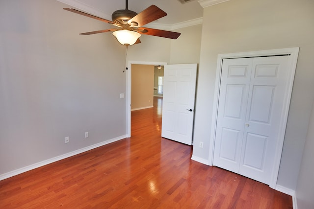 unfurnished bedroom featuring crown molding, ceiling fan, a closet, and hardwood / wood-style floors