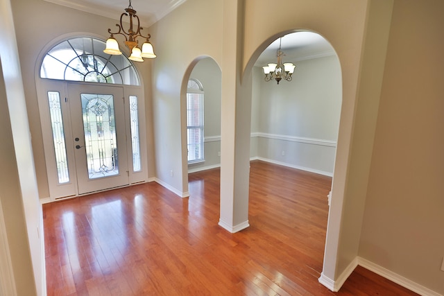 entryway with crown molding, hardwood / wood-style floors, and a chandelier