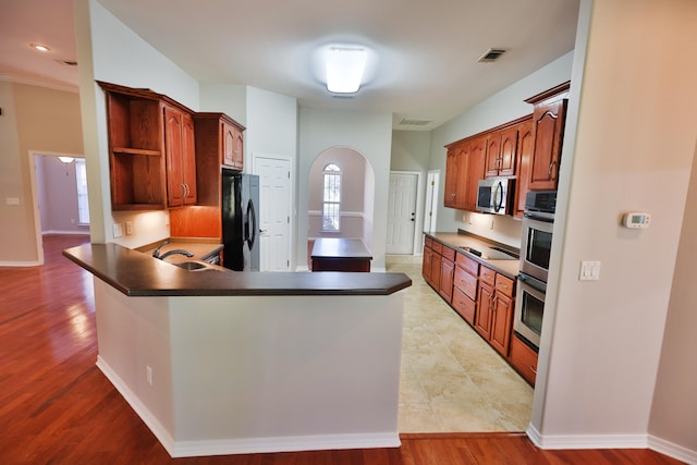 kitchen with kitchen peninsula, black appliances, sink, and light hardwood / wood-style flooring