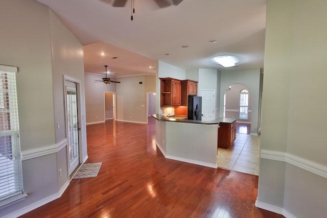 kitchen featuring ceiling fan, dark hardwood / wood-style floors, black fridge with ice dispenser, and kitchen peninsula