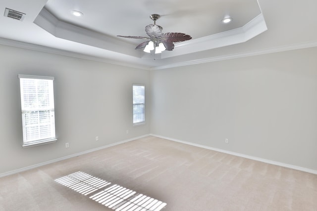 carpeted spare room with ceiling fan, crown molding, and a tray ceiling