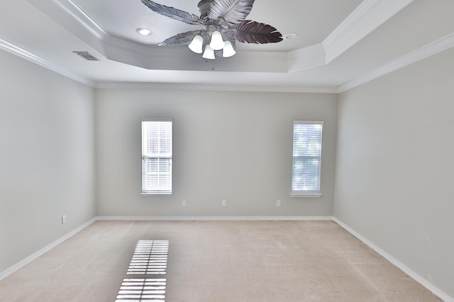 empty room featuring ceiling fan, light carpet, crown molding, and a tray ceiling