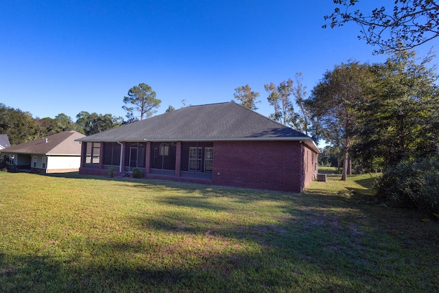 back of property featuring a sunroom and a lawn