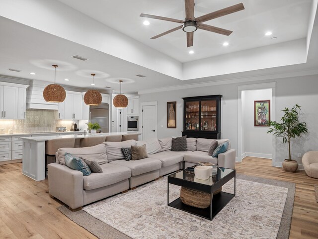 living room with light hardwood / wood-style floors, ceiling fan, and ornamental molding