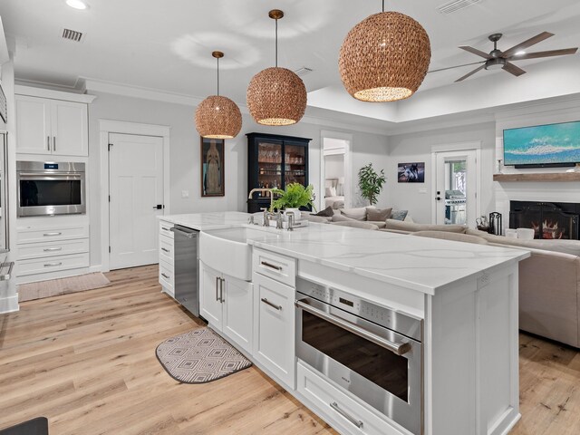 kitchen featuring white cabinetry, light hardwood / wood-style flooring, a kitchen island with sink, and appliances with stainless steel finishes