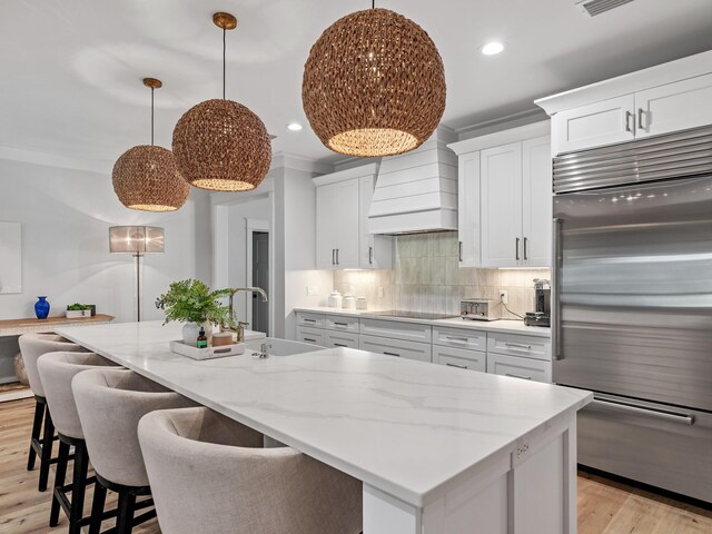 kitchen featuring white cabinetry, sink, built in refrigerator, light hardwood / wood-style floors, and custom range hood