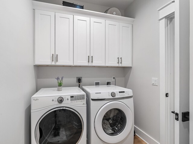 washroom with washing machine and clothes dryer and cabinets