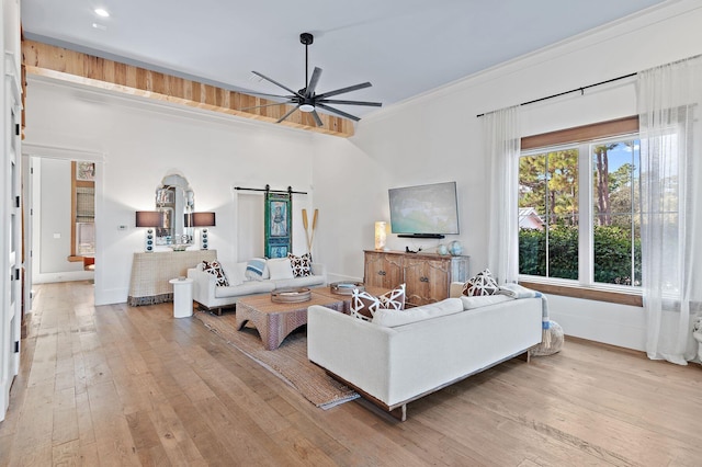 living room with ornamental molding, a barn door, light hardwood / wood-style floors, and ceiling fan