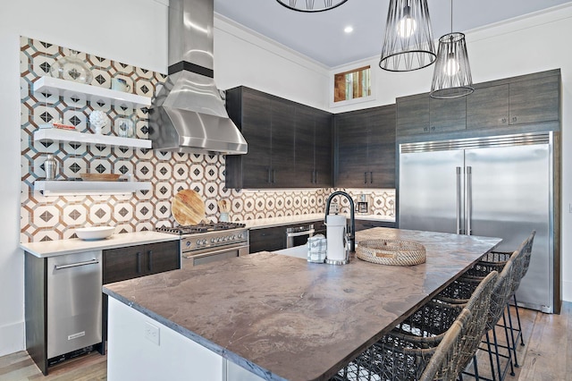 kitchen featuring high quality appliances, an island with sink, light hardwood / wood-style floors, and a breakfast bar