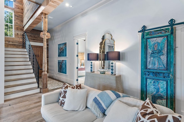 living room featuring wood walls, light hardwood / wood-style flooring, and a barn door