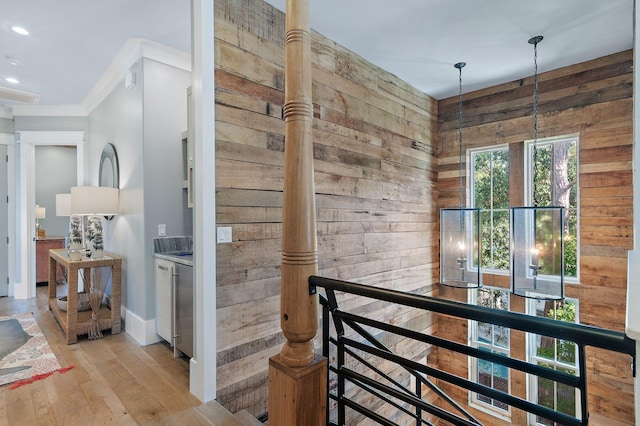 hallway featuring light hardwood / wood-style floors, wood walls, and crown molding