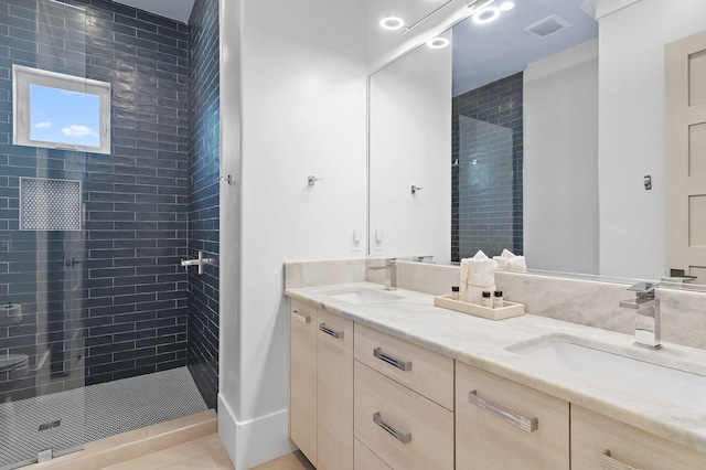 bathroom with vanity, tiled shower, and tile patterned flooring