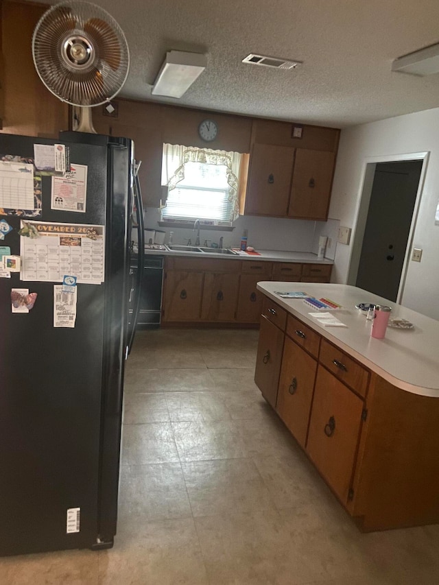 kitchen with black appliances, sink, and a textured ceiling