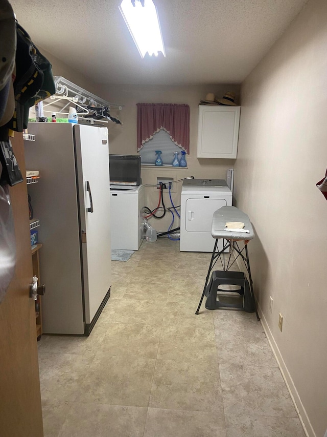 clothes washing area with cabinets, a textured ceiling, and washer / dryer