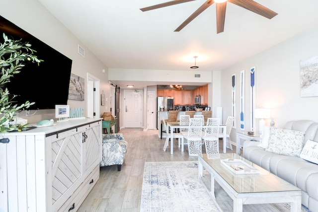 living room with ceiling fan and light hardwood / wood-style floors