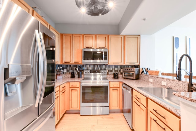 kitchen featuring light wood-type flooring, light brown cabinets, sink, backsplash, and appliances with stainless steel finishes