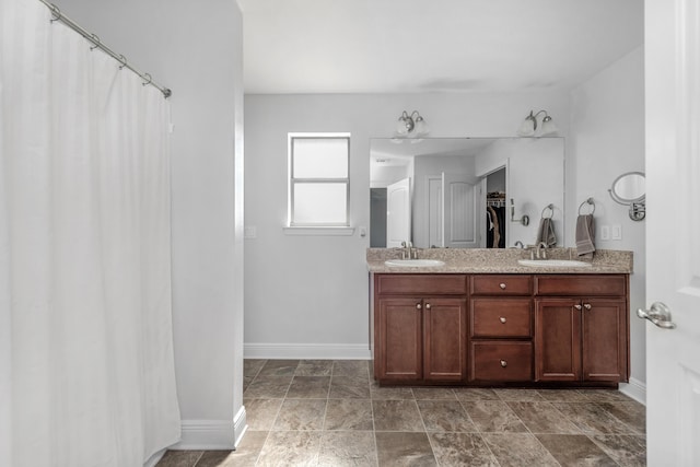 full bath featuring baseboards, double vanity, and curtained shower