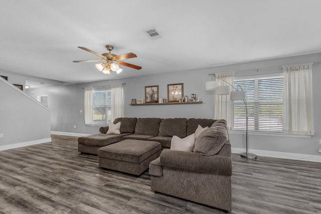 living area featuring wood finished floors, baseboards, ceiling fan, and stairs