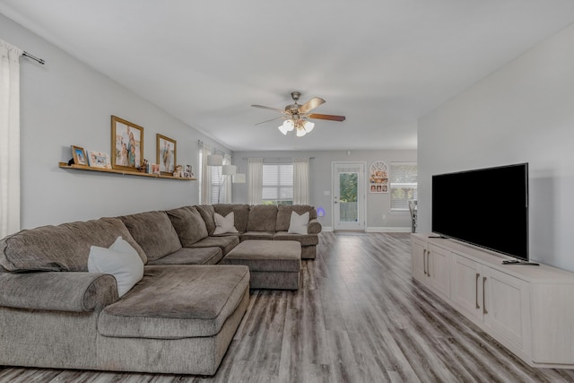 living area with light wood-type flooring, ceiling fan, and baseboards