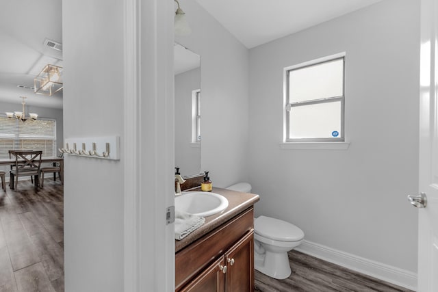 bathroom with hardwood / wood-style flooring, vanity, toilet, and a chandelier