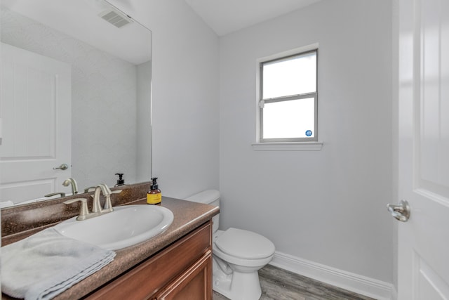 bathroom featuring wood finished floors, toilet, vanity, and baseboards