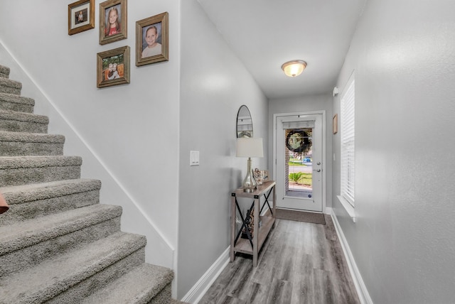 foyer entrance with stairs, wood finished floors, and baseboards
