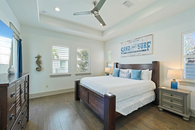 bedroom with ceiling fan, a tray ceiling, and dark hardwood / wood-style floors